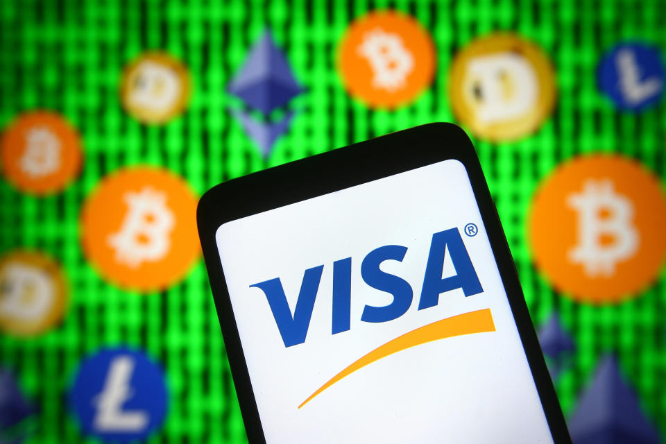 UKRAINE - 2021/04/30: In this photo illustration, the Visa logo is seen displayed on a smartphone screen in front of cryptocurrency signs.  (Photo illustration by Pavlo Gonchar/SOPA Images/LightRocket via Getty Images)