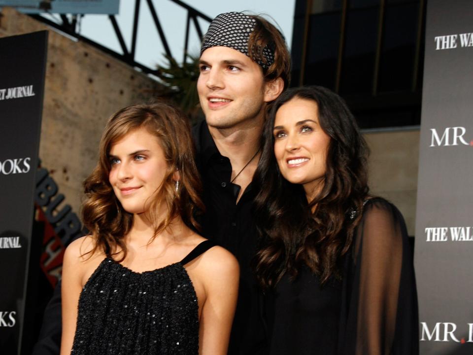 Ashton Kutcher embracing Demi Moore and Tallulah Belle posing for photographers in front of a branded backdrop for the film "Mr. Brooks"