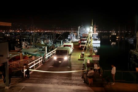 Vans carry the victims of a pre-dawn fire that sank a commercial diving boat off the coast of Santa Barbara