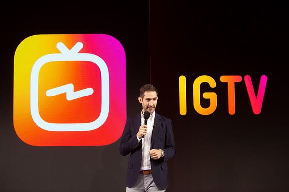 Kevin Systrom speaking on stage in front of the IGTV app icon