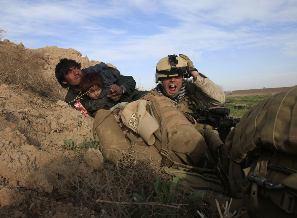 <p>U.S. Marine Lance Corporal Chris Sanderson, 24, from Flemington, New Jersey shouts as he tries to protect an Afghan man and his child after Taliban fighters opened fire in the town of Marjah, in Nad Ali district, Helmand province, Feb. 13, 2010. (Photo: Goran Tomasevic/Reuters) </p>