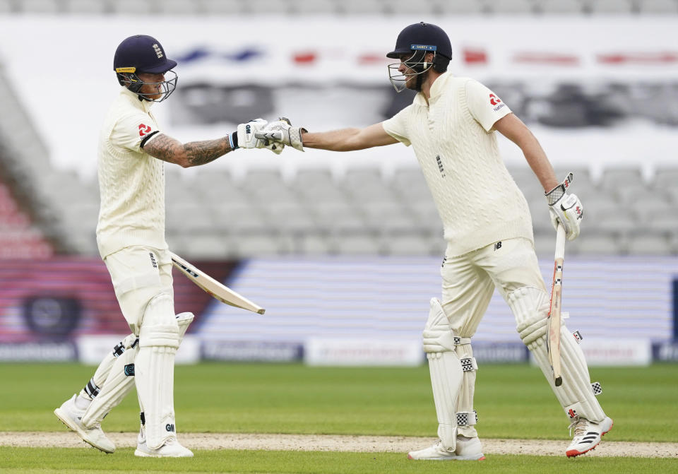 England's Ben Stokes, left, celebrates with teammate Dom Sibley after scoring fifty runs during the first day of the second cricket Test match between England and West Indies at Old Trafford in Manchester, England, Thursday, July 16, 2020. (AP Photo/Jon Super, Pool)