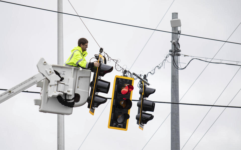 Kentucky Transportation Cabinet utility crews check on the stoplights hanging over the intersection of Cave Mill Road and Scottsville Road in Bowling Green, Ky., after another tornado warning was issued late Saturday morning, Jan. 1, 2022, for Warren and surrounding counties, following the devastating tornadoes that tore through town on Dec. 11, 2021. Though the damage from Saturday's storm proved less catastrophic than the system that passed through in December, heavy rain and strong winds battered the area, causing damage along Cave Mill Road and the surrounding area. (Grace Ramey/Daily News via AP)