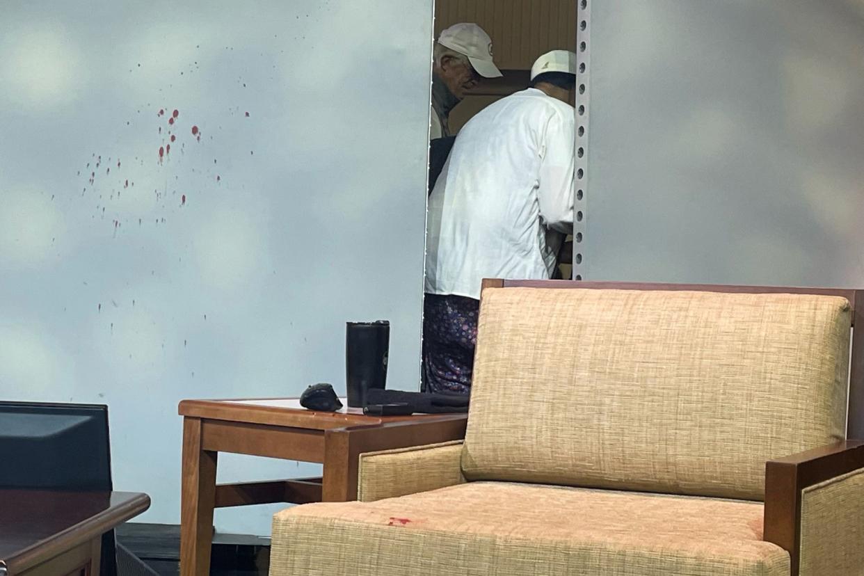 Blood stains mark a screen as author Salman Rushdie, behind screen, is tended to after he was attacked during a lecture, Friday, Aug. 12, 2022, at the Chautauqua Institution in Chautauqua, N.Y. 