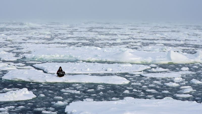 Environmental activist and campaigner Mya-Rose Craig holds a cardboard sign reading “youth strike for climate” in the middle of the Arctic Ocean