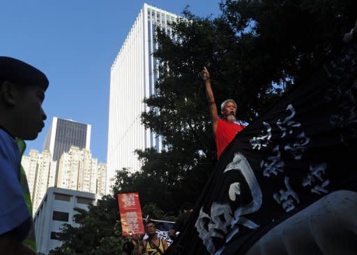 A policeman (L) watches on as a pro-democracy demonstrator (R) chants slogans calling on the Chinese government to investigate the death of dissident Li Wangyang during a protest in Hong Kong. Hong Kong installs a new leader and marks 15 years of Chinese rule Sunday, at a time of strong anti-Beijing sentiment after visiting Chinese President Hu Jintao was targeted by angry protesters