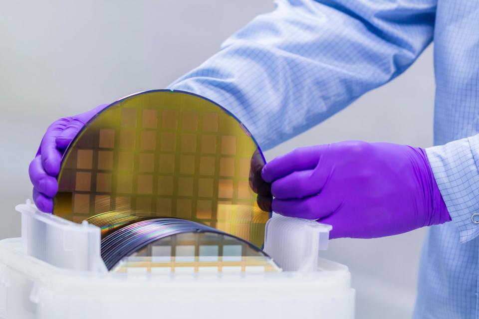 A technician places a silicon wafer in a plastic holder for further processing.