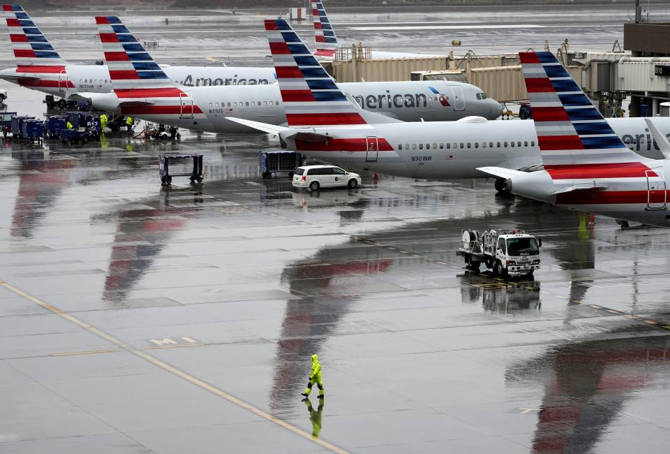 American Airlines employees guide planes and load luggage in the rain at Sky Harbor International Airport in Phoenix on Dec. 28, 2022. Weather is causing flight delays across the country.