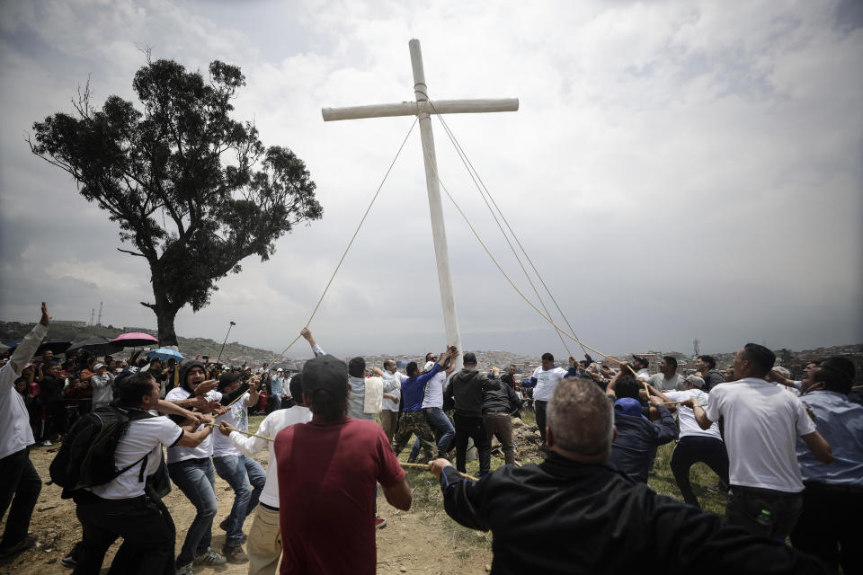 Faithful raise a giant wooden cross before the Árbol de la Vida or Tree of Life during a Good Friday procession in the hills of the Ciudad Bolivar neighborhood of Bogota, Colombia, Friday, April 7, 2023. Holy Week commemorates the last week of the earthly life of Jesus Christ culminating in his crucifixion on Good Friday and his resurrection on Easter Sunday. (AP Photo/Ivan Valencia)