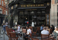 People sit outside the White Lion pub in London, Tuesday, Sept. 22, 2020. British Prime Minister Boris Johnson has slammed the brakes on the country's return to offices, saying people should work from home if possible to help slow the spread of the coronavirus. Johnson on Tuesday announced a package of new restrictions, including a requirement for pubs, restaurants and other hospitality venues in England to close between 10 p.m. and 5 a.m. (AP Photo/Frank Augstein)