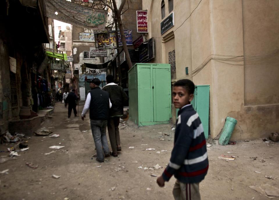 In this Monday, Nov. 26, 2012 photo, residents pass a kiosk, center, that is used as a clinic where girls are circumcised by a barber, in the Imbaba area of Giza, Egypt. Women activists say they won a major step forward with Egypt’s new constitution, which enshrined greater rights for women. But months after its passage, they’re worrying whether those rights will be implemented or will turn out to be merely ink on paper. Men hold an overwhelming lock on decision-making and are doing little to bring equality, activists say, and the increasingly repressive political climate is stifling chances for reforms. (AP Photo/Maya Alleruzzo) EGYPT OUT