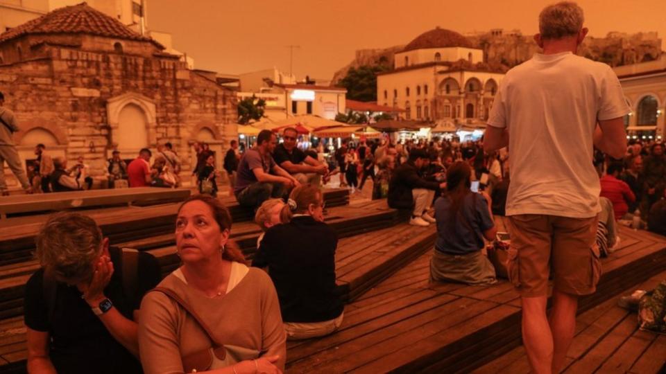 People stroll while African dust covers the sky of Athens, Greece