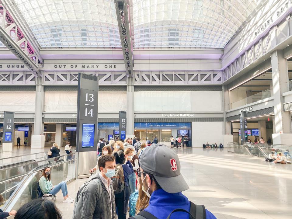 People wait in line to board at Penn Station