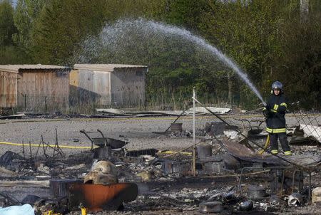 A French fireman extinguish debirs of shelters the day after a fire destroyed large swathes of the Grande-Synthe migrant camp near Dunkirk in northern France April 11, 2017 following skirmishes on Monday that injured several people. REUTERS/Pascal Rossignol