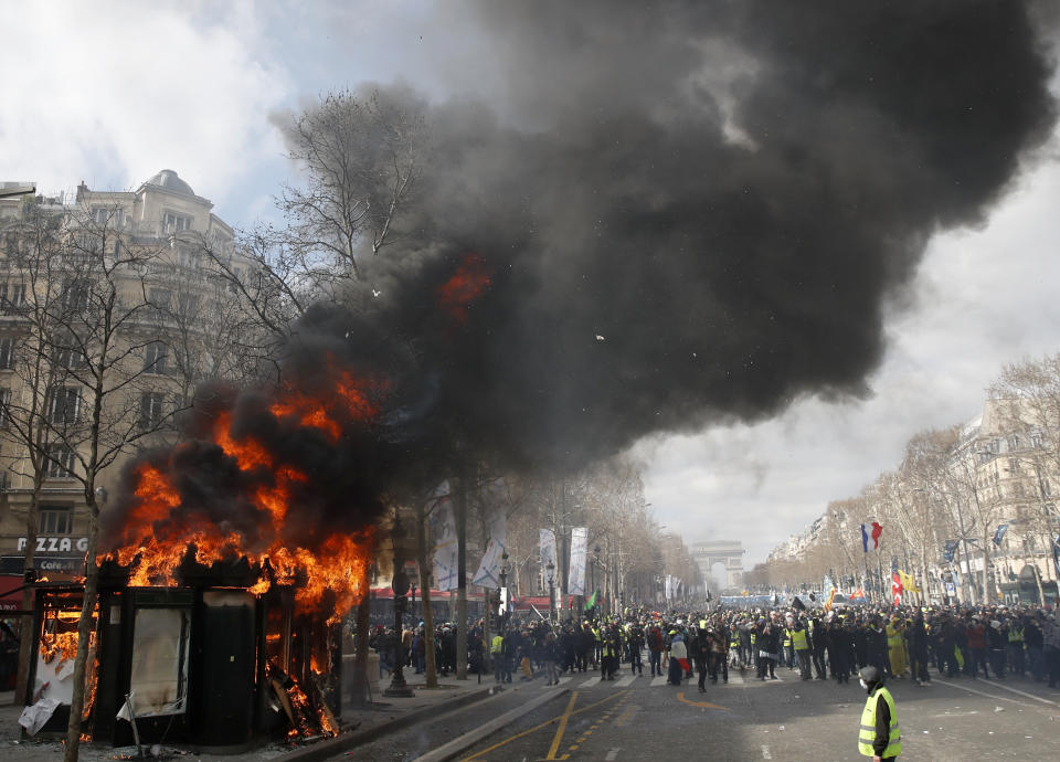 A news stand burns during a yellow vests demonstration on the Champs Elysees avenue Saturday, March 16, 2019 in Paris. French yellow vest protesters clashed Saturday with riot police near the Arc de Triomphe as they kicked off their 18th straight weekend of demonstrations against President Emmanuel Macron. (AP Photo/Christophe Ena)