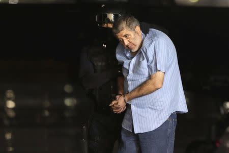 A federal policeman escorts Vicente Carrillo, drug kingpin of the Juarez Cartel, at the hangar belonging to the office of the Attorney's General in Mexico City October 9, 2014. REUTERS/Tomas Bravo