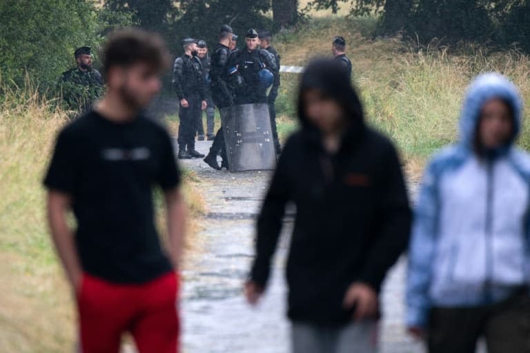 Des teufeurs passent devant les forces de l'ordre dans un champ près du lieu de la rave-party illégale organisée à Redon, en Ille-et-Vilaine, le 19 juin 2021 - LOIC VENANCE © 2019 AFP