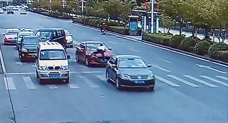 The husband climbs onto his wife's car bonnet in a bid to make her stop and get out.