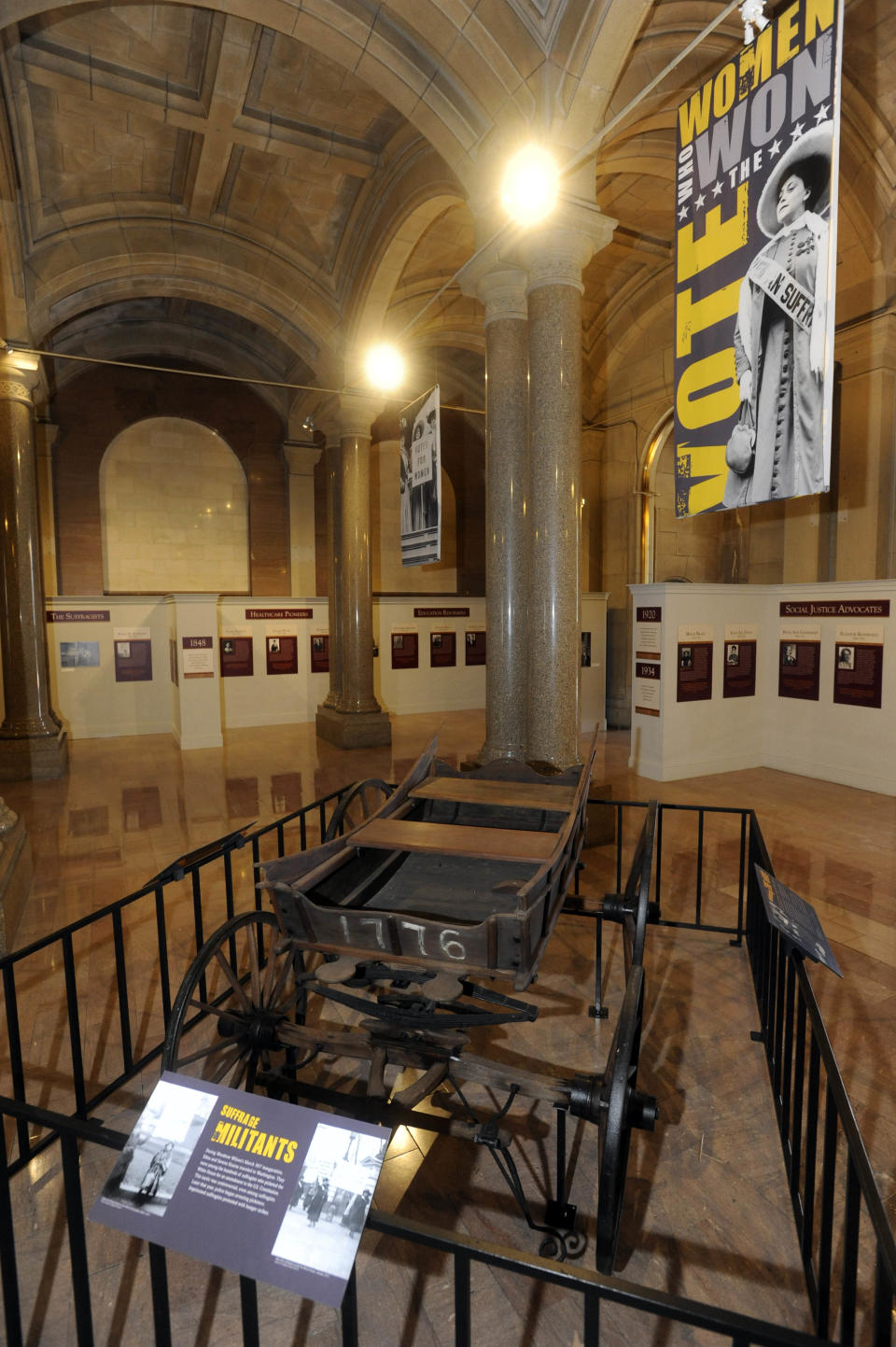 In this July 31, 2012 photo, a wagon used by women during the suffrage movement displays as the centerpiece of an exhibit entitled "From Seneca Falls to the Supreme Court: New York's Women Leading the Way" at the Capitol in Albany, N.Y. Historic artifacts that have been kept in storage for years are now on display in the corridors of the Capitol and the adjacent Empire State Plaza. (AP Photo/Tim Roske)