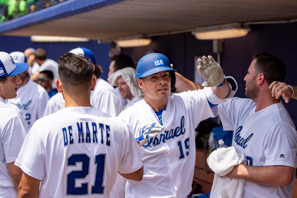 Danny Valencia (19) gets high fives in the dugout of the Israeli Olympic team.