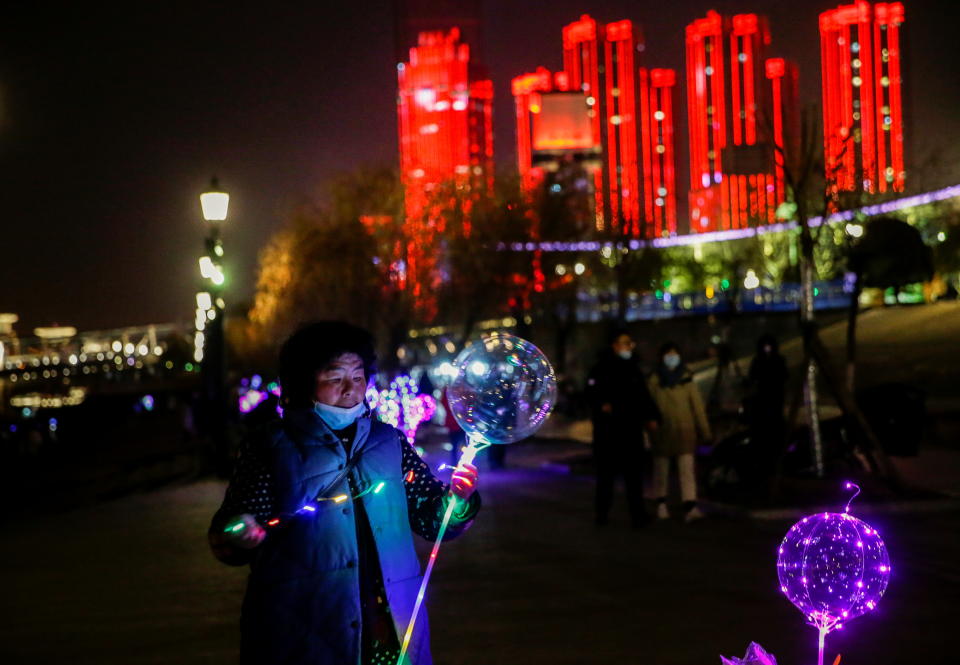 A vendor decorates a balloon for sale by a river on New Year's Eve in Wuhan (Reuters)