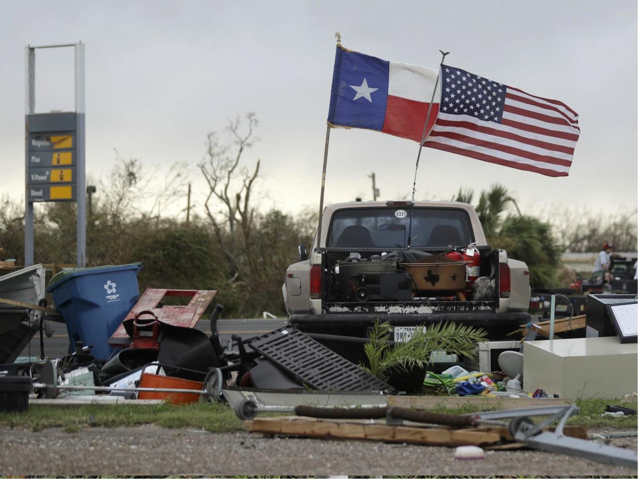 The Texas state flag and American flag wave in the wind over an area of debris left behind in the wake of Hurricane Harvey: AP Photo/Eric Gay