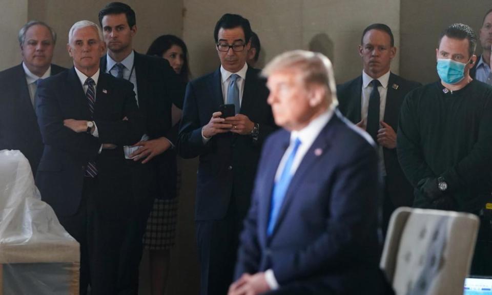 Vice-President Mike Pence and the treasury secretary, Steven Mnuchin, with phone, watch as Donald Trump participates in a live Fox News virtual town hall called ‘America Together: Returning to Work’.