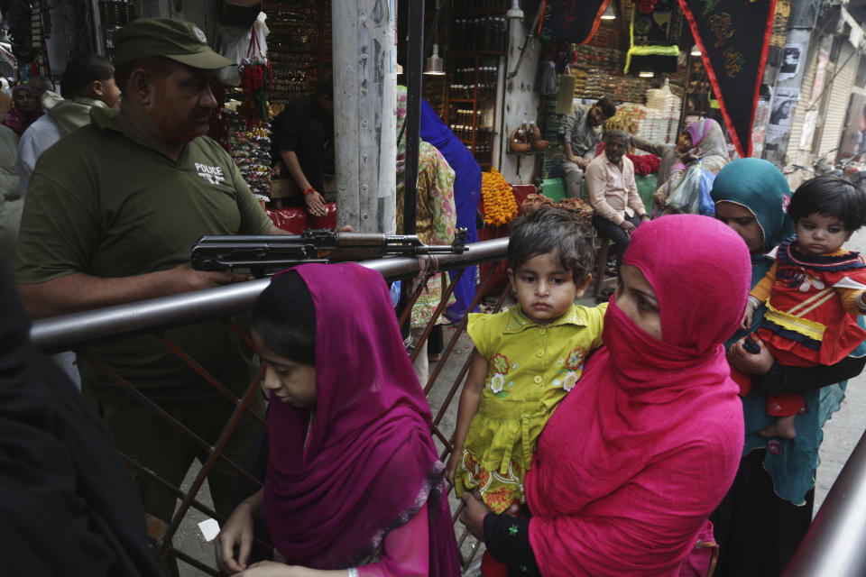 In this Wednesday, Oct. 31, 2018, photo a Pakistani police officer stands alert as devotees visit the shrine of Bibi Pakistani Daman in Lahore, Pakistan. (AP Photo/K.M. Chaudary)