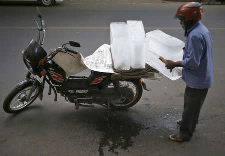 A vendor prepares to carry blocks of ice stacked on his motorcycle, to supply a market on a hot summer day in New Delhi, June 2, 2015. REUTERS/Anindito Mukherjee