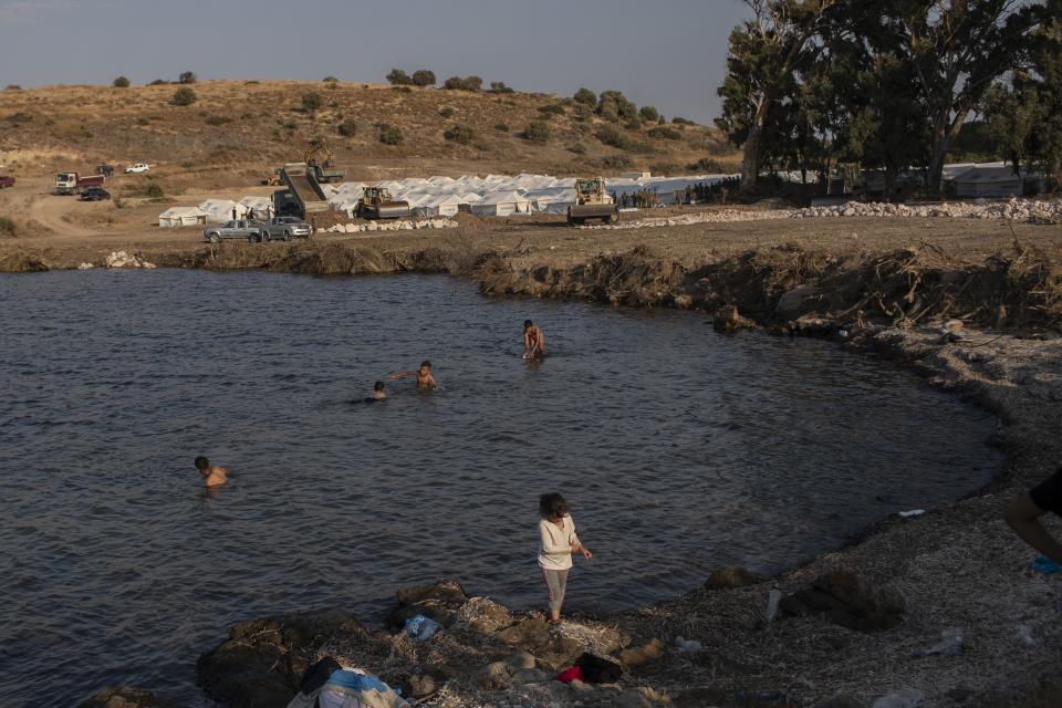 Migrants enjoy the sea next to a temporary camp near Mytilene town, on the northeastern island of Lesbos, Greece, Saturday, Sept. 12, 2020. Greek authorities have been scrambling to find a way to house more than 12,000 people left in need of emergency shelter on the island after the fires deliberately set on Tuesday and Wednesday night gutted the Moria refugee camp. (AP Photo/Petros Giannakouris)