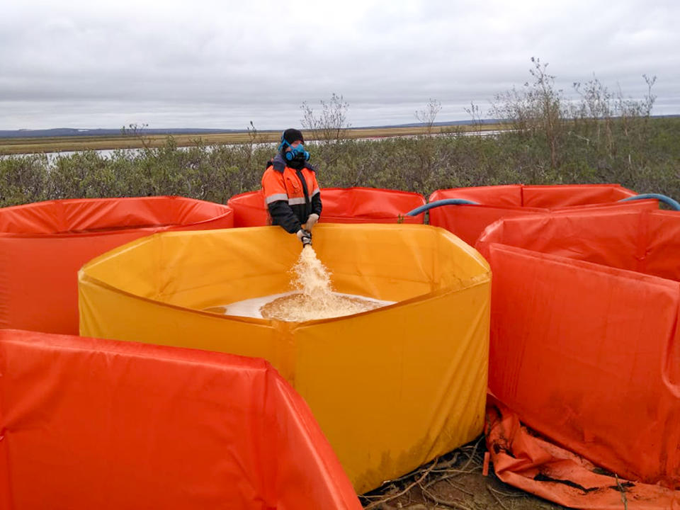 In this handout photo provided by the Russian Marine Rescue Service, a rescuer works collecting oil contaminated water from an oil spill outside Norilsk, 2,900 kilometers (1,800 miles) northeast of Moscow, Russia, on Friday, June 5, 2020. Russian President Vladimir Putin has declared a state of emergency in a region of Siberia after an estimated 20,000 tons of diesel fuel spilled from a power plant storage facility and fouled waterways.(Russian Marine Rescue Service via AP)