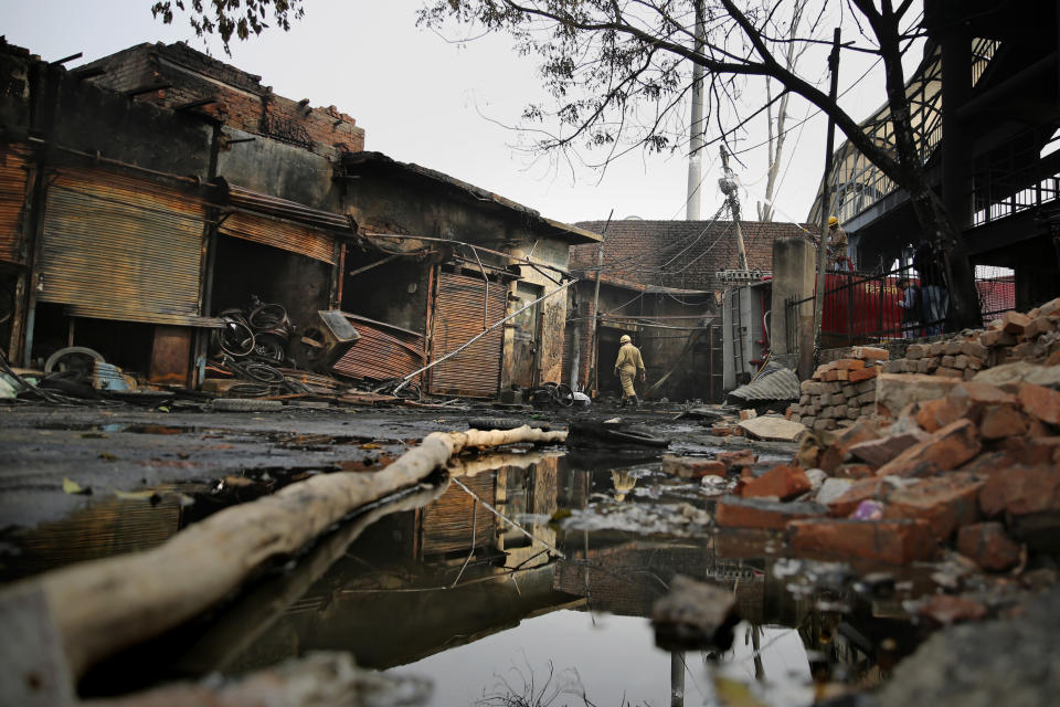 A fire fighter walks at the Gokul Puri tyre market which was burnt in Tuesday's violence in New Delhi, India, Wednesday, Feb. 26, 2020. At least 20 people were killed in three days of clashes in New Delhi, with the death toll expected to rise as hospitals were overflowed with dozens of injured people, authorities said Wednesday. The clashes between Hindu mobs and Muslims protesting a contentious new citizenship law that fast-tracks naturalization for foreign-born religious minorities of all major faiths in South Asia except Islam escalated Tuesday. (AP Photo/Altaf Qadri)