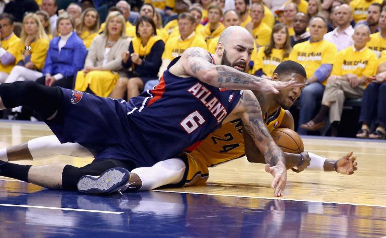 Pero Antic (L) of the Atlanta Hawks and Paul George of the Indiana Pacers battle for a loose ball in Game 1 of the Eastern Conference Quarterfinals during the 2014 NBA Playoffs at Bankers Life Fieldhouse on April 19, 2014 which the Hawks won 101-93