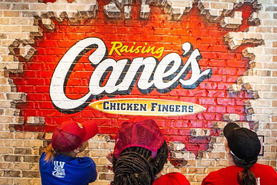 Trainees observe the logo of Raising Cane's at The Grove (formerly College Square shopping center) in Newark, Thursday, April 13, 2023. 