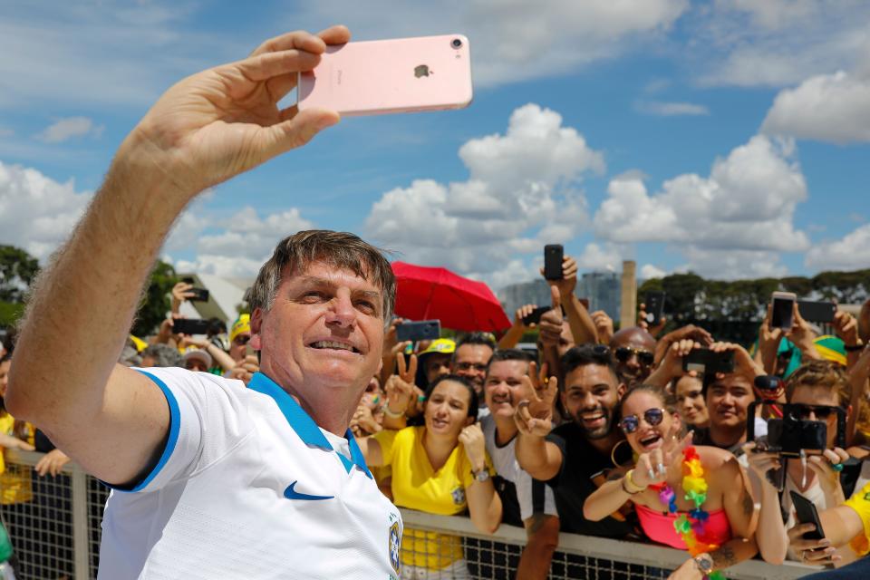Brazilian President Jair Bolsonaro takes a selfie with supporters in front of the Planalto Palace on March 15, 2020.&nbsp; (Photo: Photo by SERGIO LIMA/AFP via Getty Images)