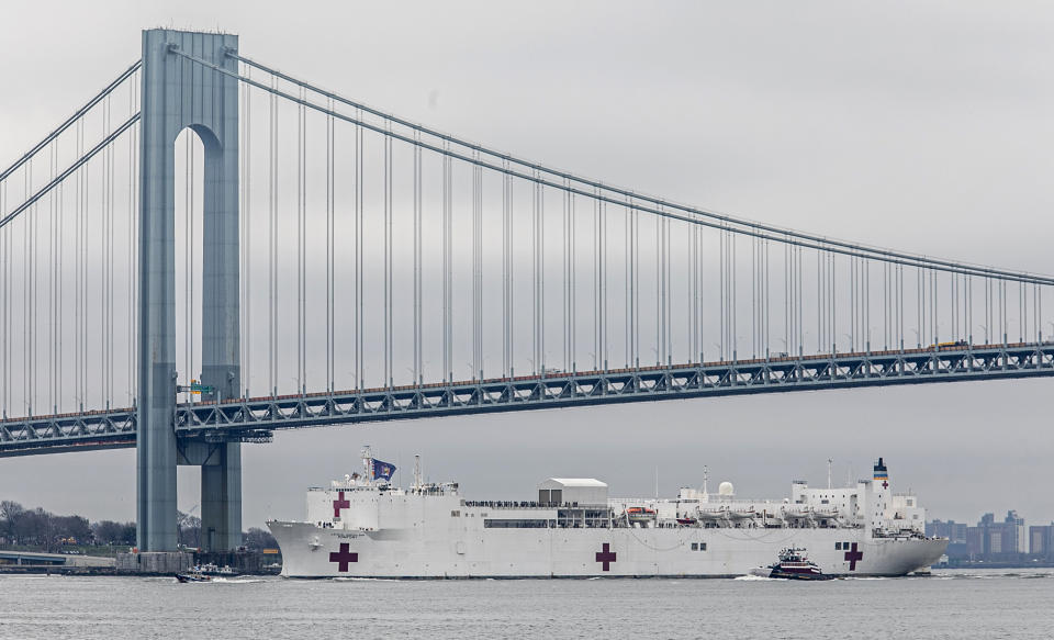 FiLE- In this March 30, 2020 file photo, the Navy hospital ship USNS Comfort passes under the Verrazzano-Narrows Bridge on its way to docking in New York. On Tuesday, April 21, 2020, while expressing confidence that stresses on New York City's hospital system are easing, New York Gov. Andrew Cuomo said that the ship deployed to New York City to help fight the coronavirus outbreak is no longer needed. (AP Photo/Bebeto Matthews, File)