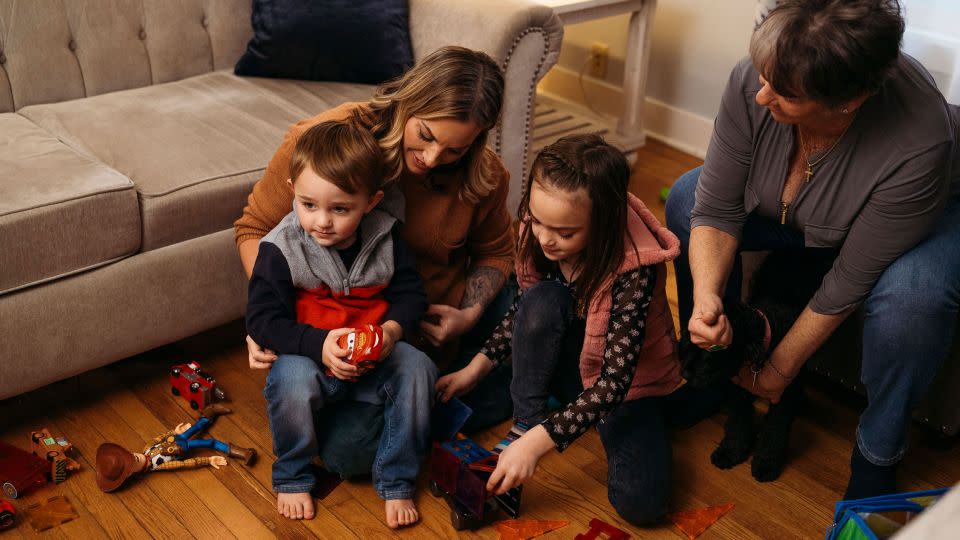 Victoria Hill and her two children play with toys in the living room of her mother's house in Wethersfield. - Laura Oliverio/CNN