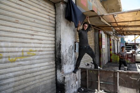 A shop owner puts a black flag in front of his closed shop during a strike called by local activists against U.S. President Donald Trump's "Deal of the Century" at Al-Baqaa Palestinian refugee camp, near Amman