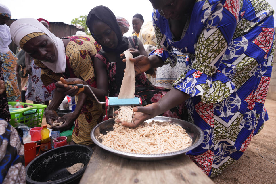 Women learn how to prepare Spaghetti that will boost their families' nutrient intake with orange-fleshed sweet potato, in Kaltungo Poshereng Nigeria, Sunday, June 2, 2024. More than a dozen women gathered this week in Kaltungo's Poshereng village where they are learning at least 200 recipes they can prepare with those local foods which, in the absence of rain, are grown in sand-filled sacks that require small amounts of water. The training session mirrored the struggles of households who are more challenged amid Nigeria's worst cost of living crisis. (AP Photo/Sunday Alamba)