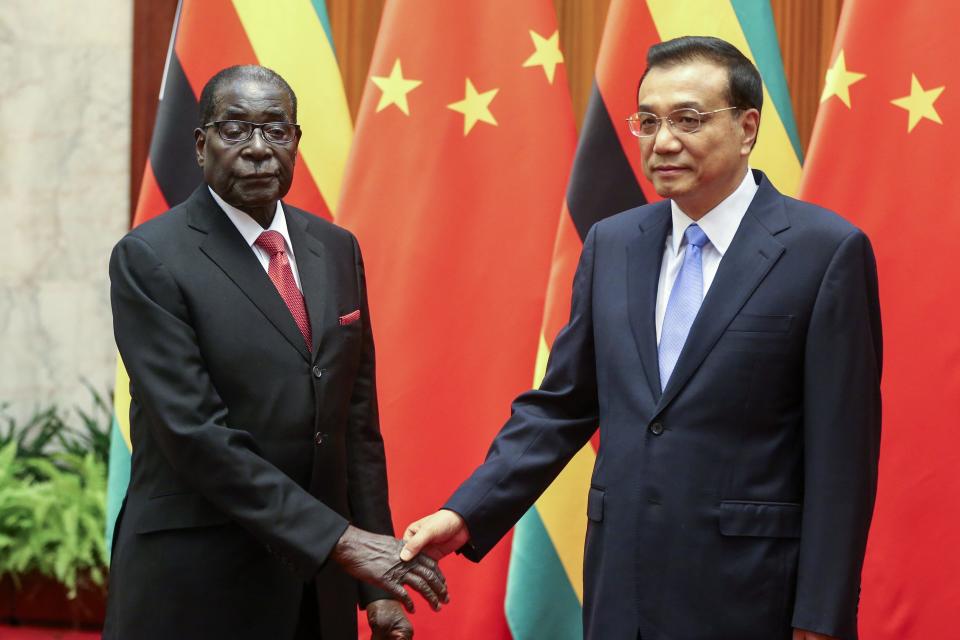 Zimbabwe's President Robert Mugabe (L) and China's Premier Li Keqiang shake hands during their meeting at the Great Hall of the People in Beijing 26 August, 2014. Mugabe, at 90 Africa's oldest leader and one of its longest-serving, is visiting China this week. Officials say he will seek funds to rebuild decaying roads, rail and power facilities and to help mechanise Zimbabwe's agriculture. Official data show China has extended $1 billion in loans to Zimbabwe since 2009 and trade between the two nations rose to $1 billion last year from $300 million five years ago. REUTERS/Diego Azubel/Pool (CHINA - Tags: POLITICS BUSINESS)