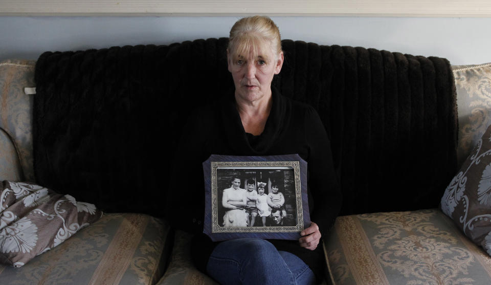 FILE- In this Thursday, Jan. 12, 2012 file photo, Helen McKendry holds a family photograph showing her mother Jean McConville at home in Killyleagh, Northern Ireland. Northern Ireland police say they have charged a 77-year-old man with involvement in the Irish Republican Army’s 1972 abduction, killing and secret burial of a Belfast woman, an unsolved case linked to Sinn Fein leader Gerry Adams. The man was scheduled to be arraigned Saturday on charges of IRA membership and aiding the killers of Jean McConville, a widowed mother of 10. The IRA accused the 38-year-old of spying for British forces, abducted her at gunpoint from her home, and shot her in the back of the head. The IRA admitted responsibility in 1999. Her unmarked grave was discovered four years later in the Republic of Ireland. Two former IRA members since have accused Adams, a senior Belfast IRA figure in 1972, of ordering McConville’s execution. Adams denies any involvement. (AP Photo/Peter Morrison, file)