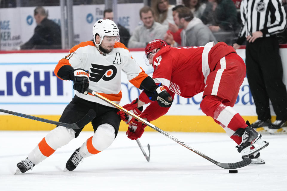 Detroit Red Wings defenseman Filip Hronek (17) knocks Philadelphia Flyers center Scott Laughton (21) off the puck in the second period of an NHL hockey game Saturday, Jan. 21, 2023, in Detroit. (AP Photo/Paul Sancya)