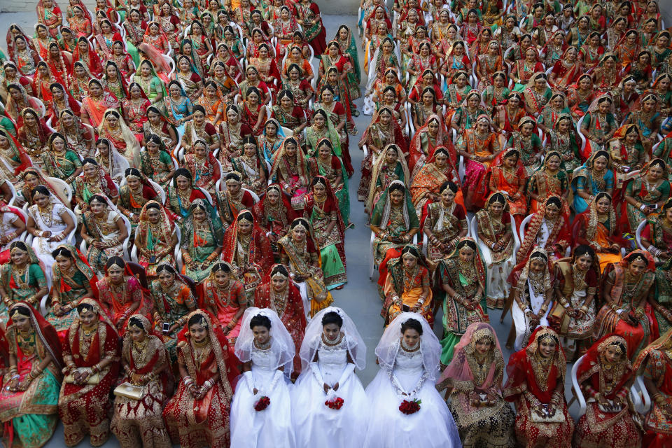 In this Sunday, Dec. 23, 2018, file photo, Indian brides sit together for a group photograph during a mass wedding in Surat, India. Two hundred and sixty one young couples, including six Muslim and three Christian couples tied the knot at the mass wedding hosted by Indian businessman Mahesh Savani, who has been funding the weddings of fatherless girls in the city of Surat for several years. Weddings in India are expensive affairs with the bride's family traditionally expected to pay the groom a large dowry of cash and gifts. (AP Photo/Ajit Solanki, File)