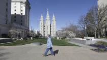 A woman walks past the Salt Lake Temple at Temple Square during The Church of Jesus Christ of Latter-day Saints' twice-annual church conference Saturday, April 4, 2020, in Salt Lake City.The twice-annual conference kicked off Saturday without anyone attending in person and top leaders sitting some 6 feet apart inside an empty room viewed via live-stream as the faith takes precautions to avoid the spread of the coronavirus. It is the first conference without a crowd since World War II, when wartime travel restrictions were in place. (AP Photo/Rick Bowmer)