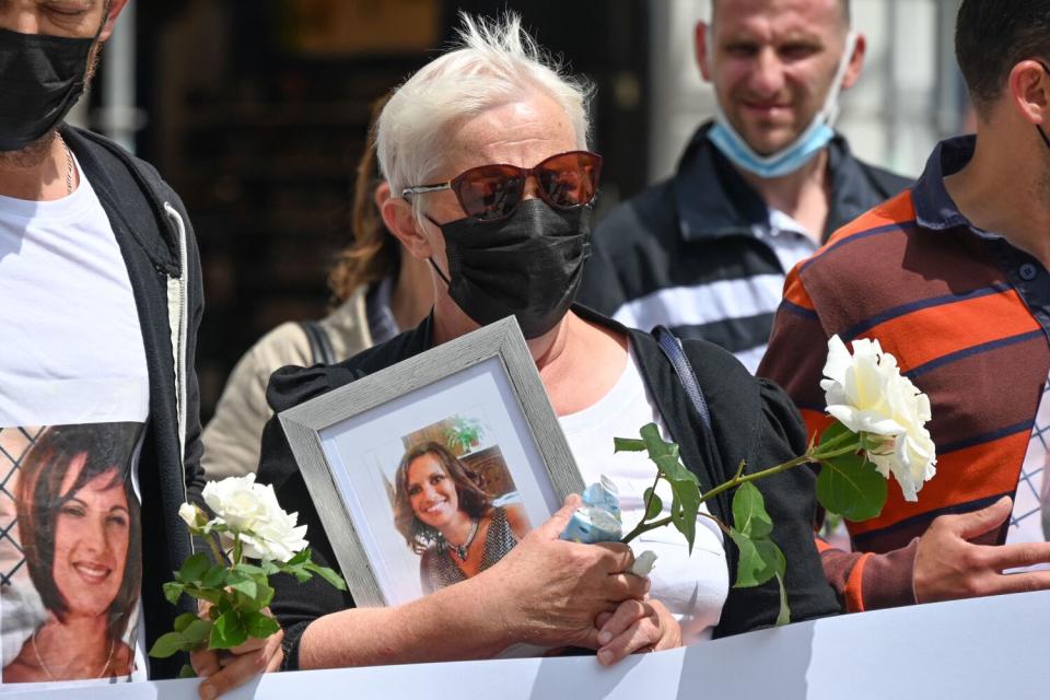 Woman holding flower and portrait at a protest