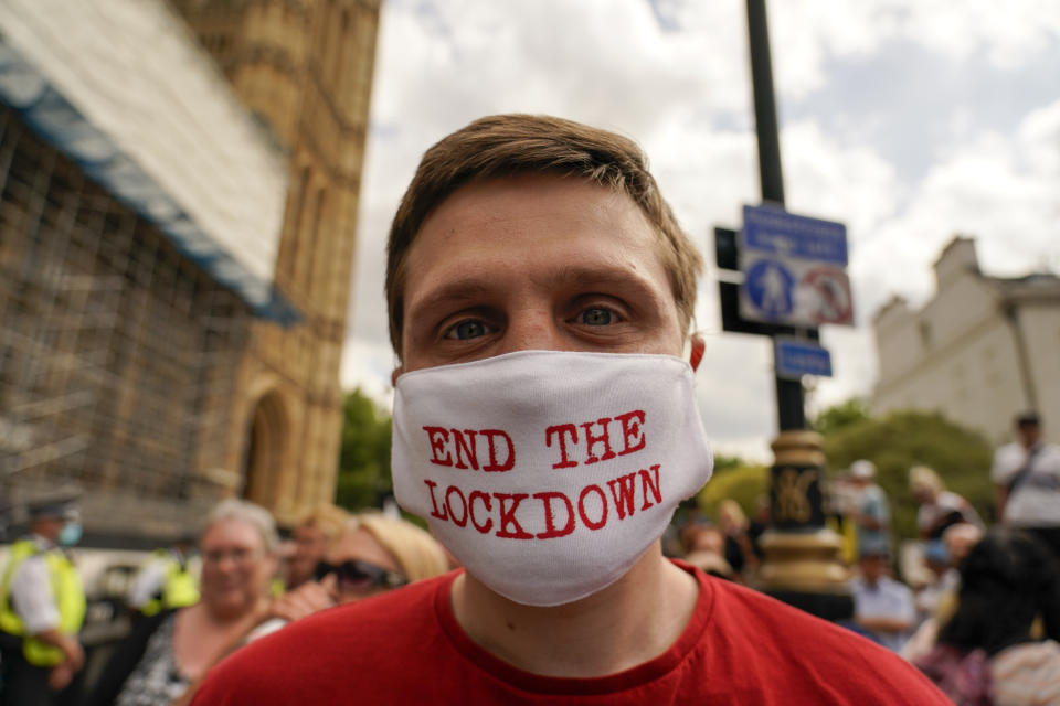 A man wears a mask reading 'End the lockdown' outside the Palace of Westminster, to protest against the delay of the planned relaxation of lockdown measures, in London, Monday, June 14, 2021. British Prime Minister Boris Johnson is expected to confirm Monday that the next planned relaxation of coronavirus restrictions in England will be delayed as a result of the spread of the delta variant first identified in India. (AP Photo/Alberto Pezzali)