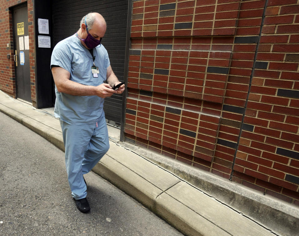 Dr. Michael Saag, who survived COVID-19 and now treats patients with the disease, checks his phone in Birmingham, Ala. Saag, who specializes in infectious diseases, is getting increasingly frustrated as many in the public flout measures meant to prevent the spread of the illness caused by the new coronavirus. (AP Photo/Jay Reeves)