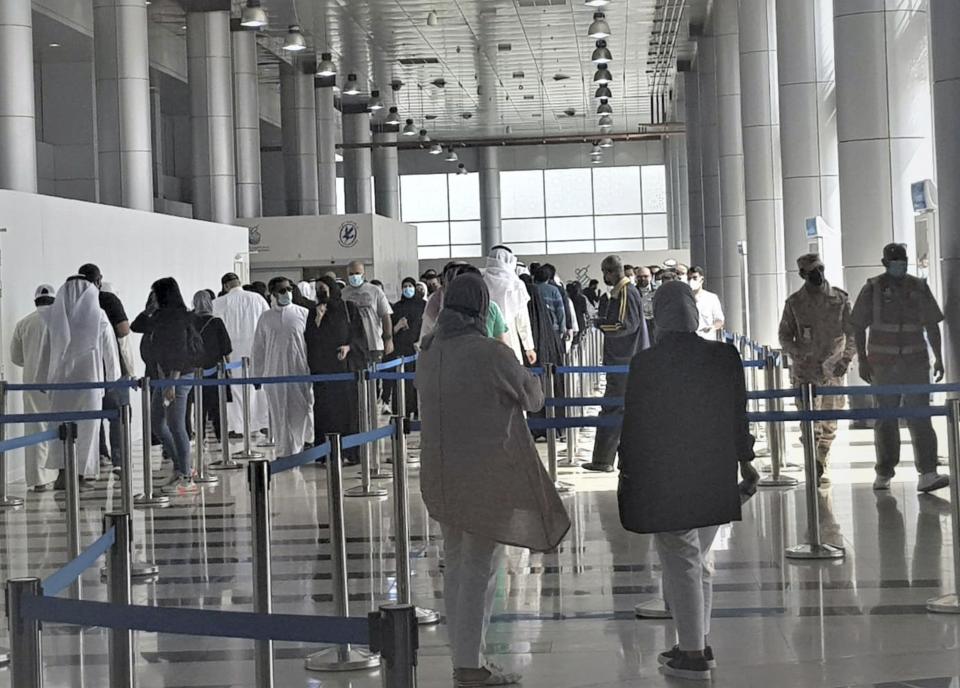 In this Friday, March 12, 2021 photo released by Kuwait News Agency, KUNA, people stand in line at Kuwait Vaccination Centre to get the vaccine in Kuwait. In the tiny, oil-rich sheikhdom of Kuwait, the foreigners who power the country's economy, serve its society and make up 70% of its population are struggling to get COVID-19 vaccines. (KUNA via AP)