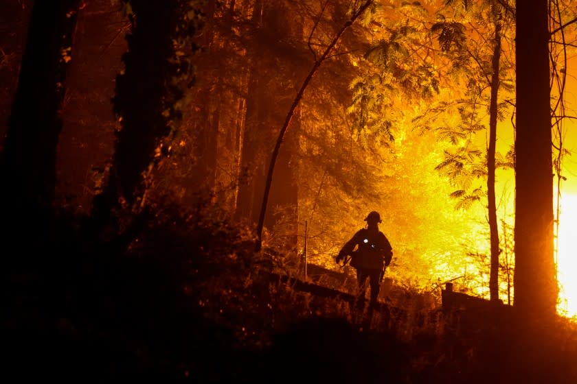 Firefighters respond to a structure fire along Riverdale Blvd. during the CZU Lightning complex fire on Sunday.