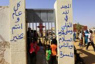 South Sudanese Christians living in the North gather to attend Christmas day celebrations at a Catholic church in the Umbada locality of Omdurman December 25, 2013. The writings on the wall read, "Glory to God in the highest heaven, and on earth peace to those on whom his favor rests" (R) and "Happy New Year" (L). REUTERS/Mohamed Nureldin Abdallah (SUDAN - Tags: RELIGION)